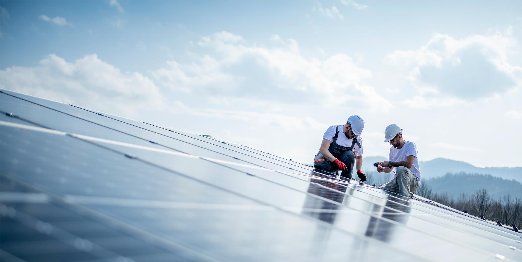 technicians on a roof installing solar panels