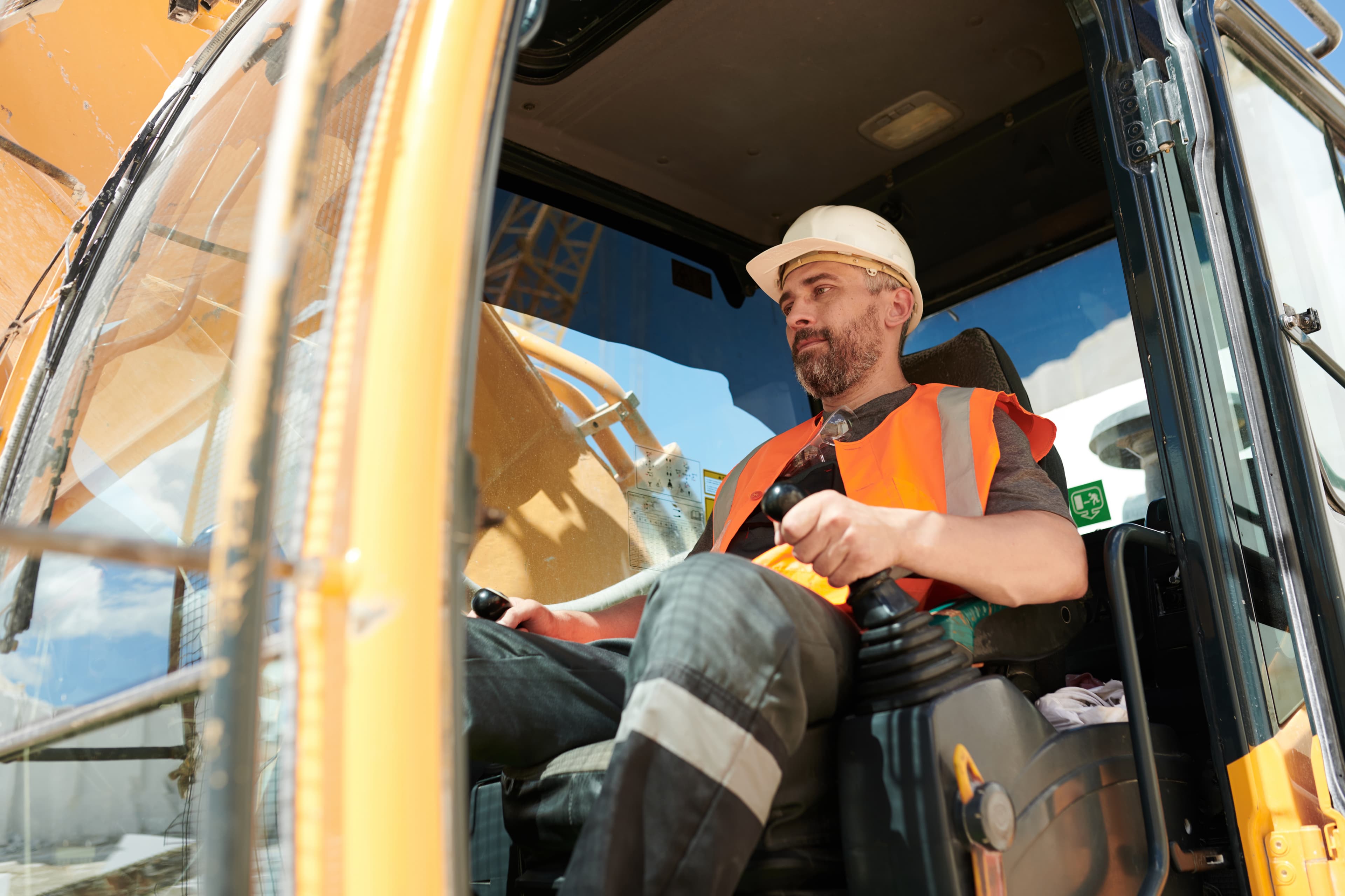 Man sitting in the excavator with hardhat on