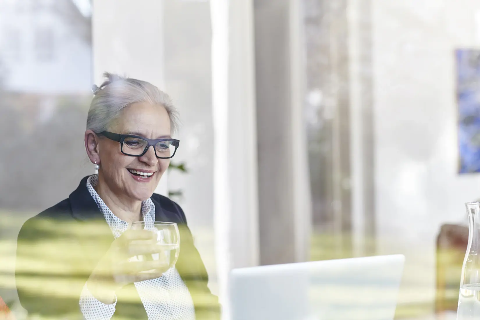 Home window view of senior businesswoman looking at laptop