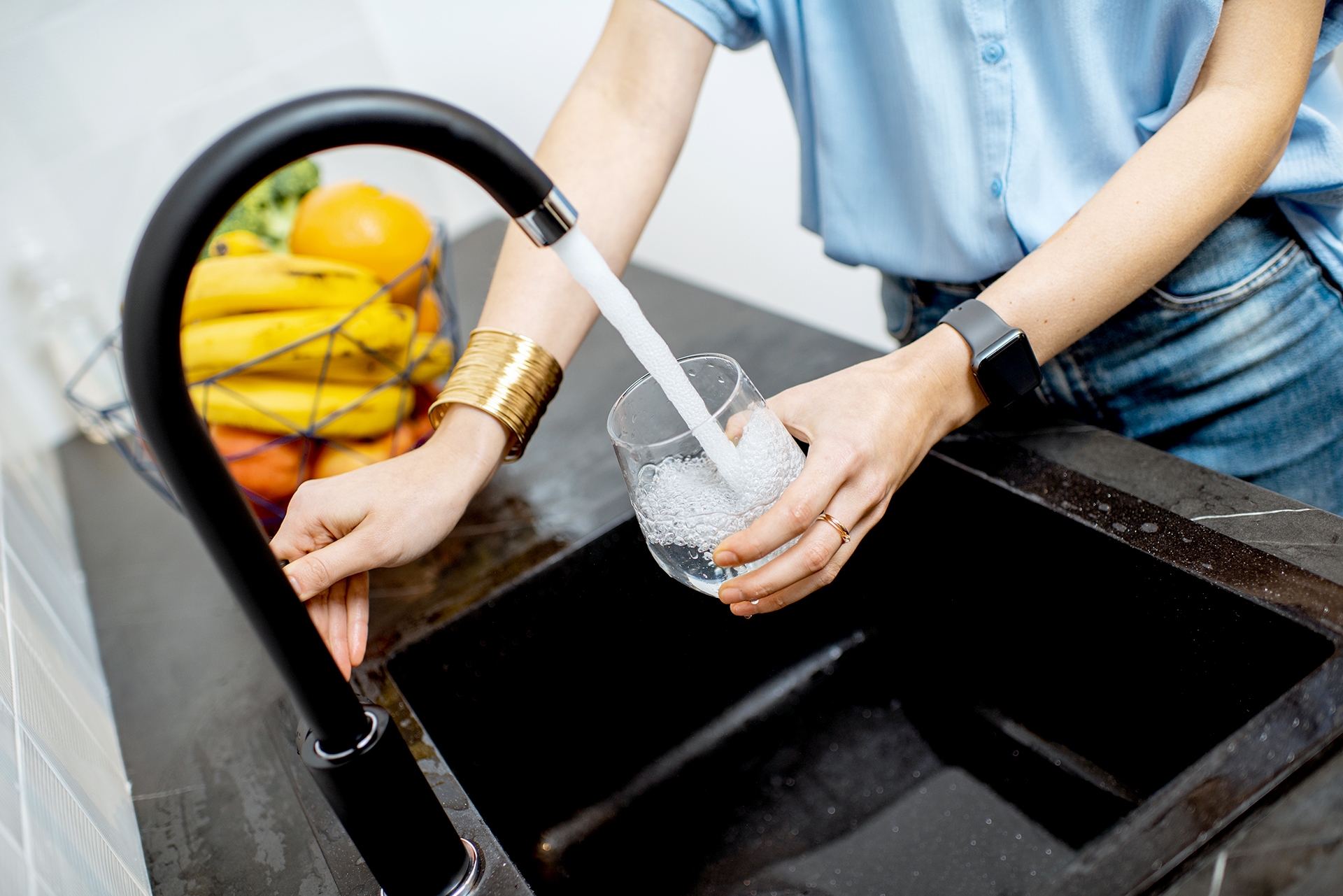 Person using sink to fill a glass of water