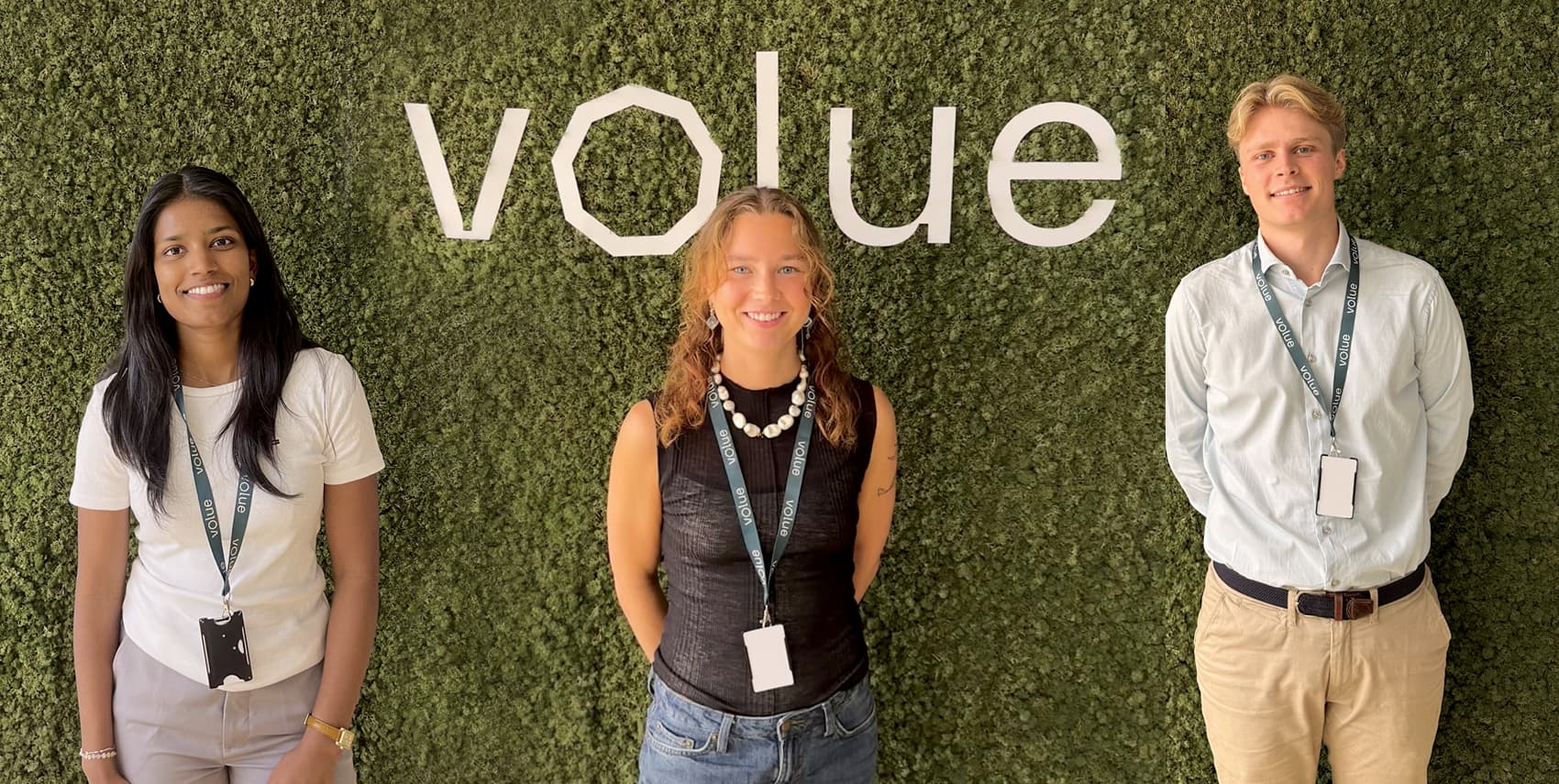 A picture of three Volue interns in front of the logo