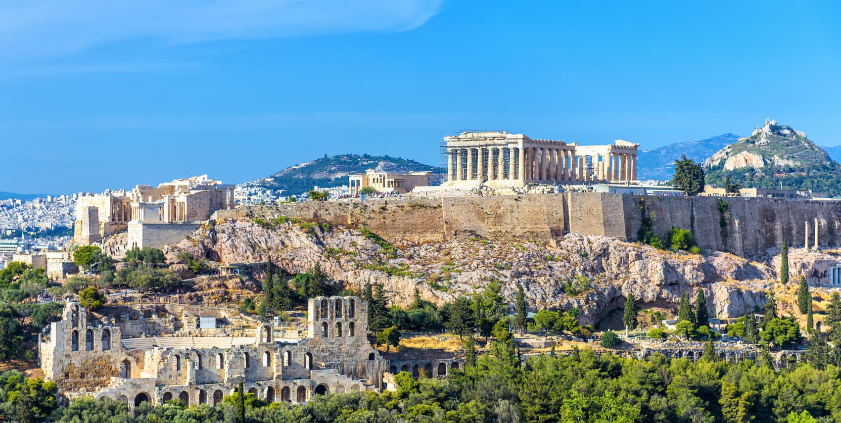 The Acropolis of Athens in Greece with the Parthenon temple and ancient ruins, a top historic landmark and popular travel destination surrounded by the modern city and green hills.